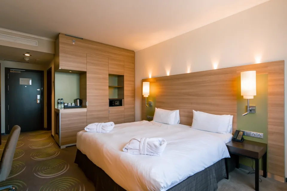 Olimpia cleaners vacuuming and turning down the bed in a hotel-style bedroom